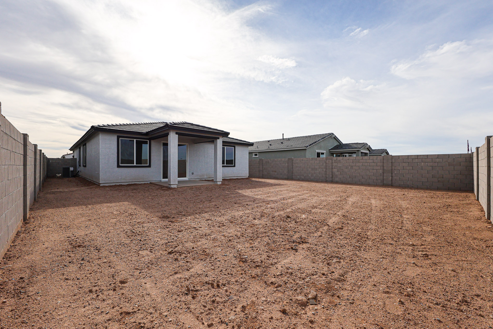 A dirt yard with a house in the background.