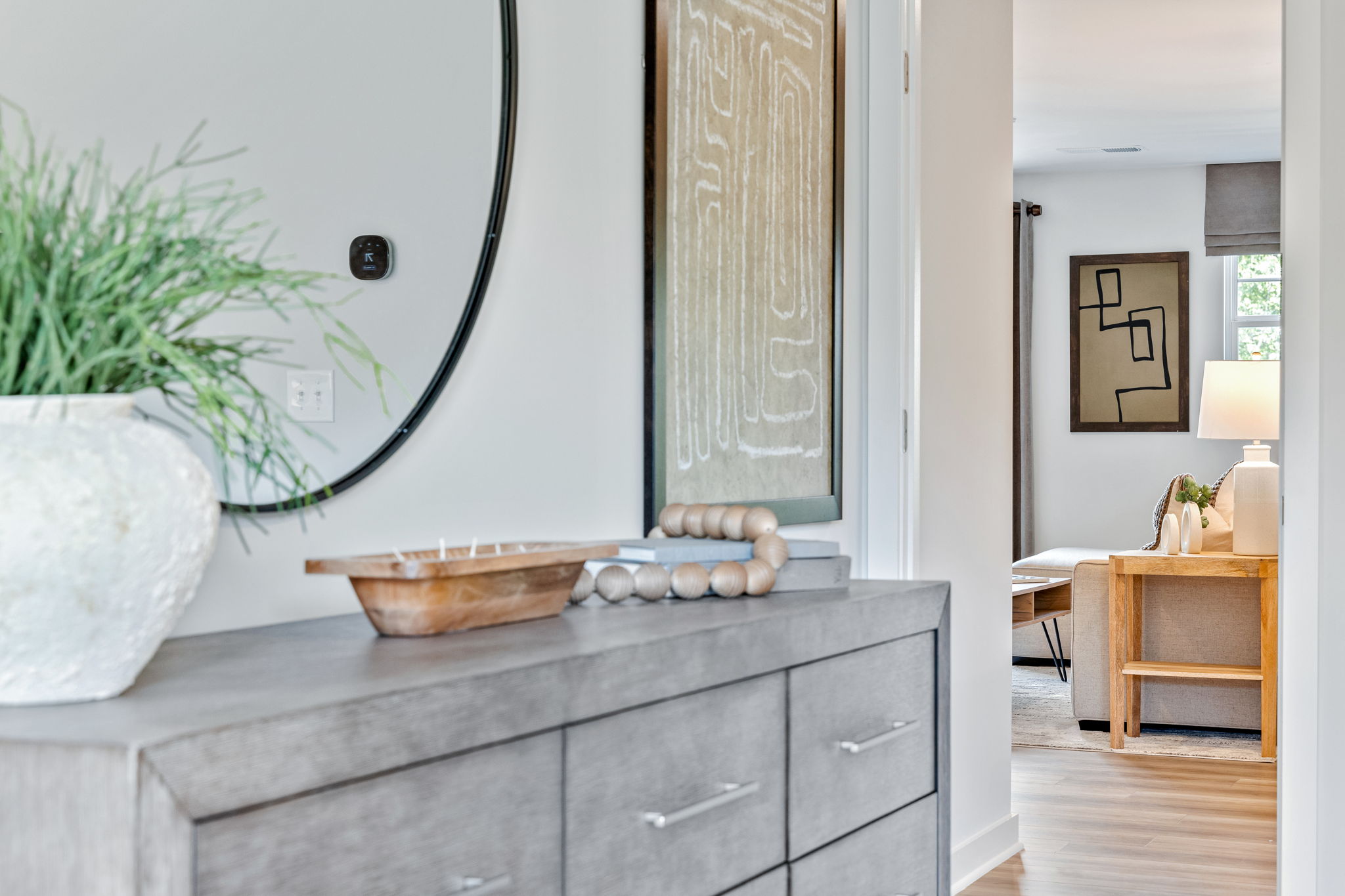 A room with a plant and a cabinet with objects on it.