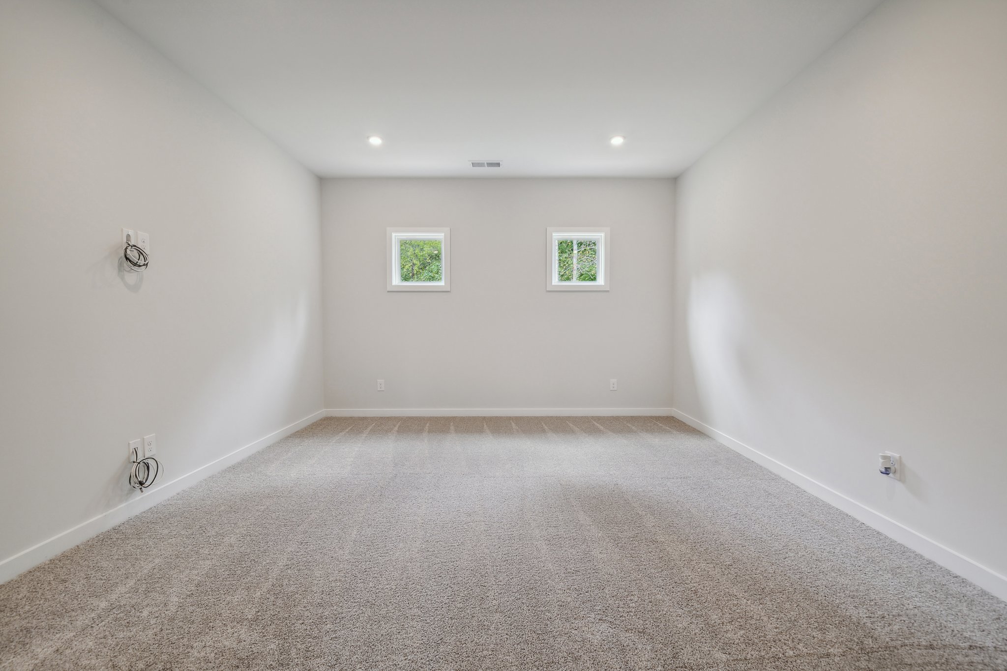 A room with a carpet and a white wall with pictures on it.