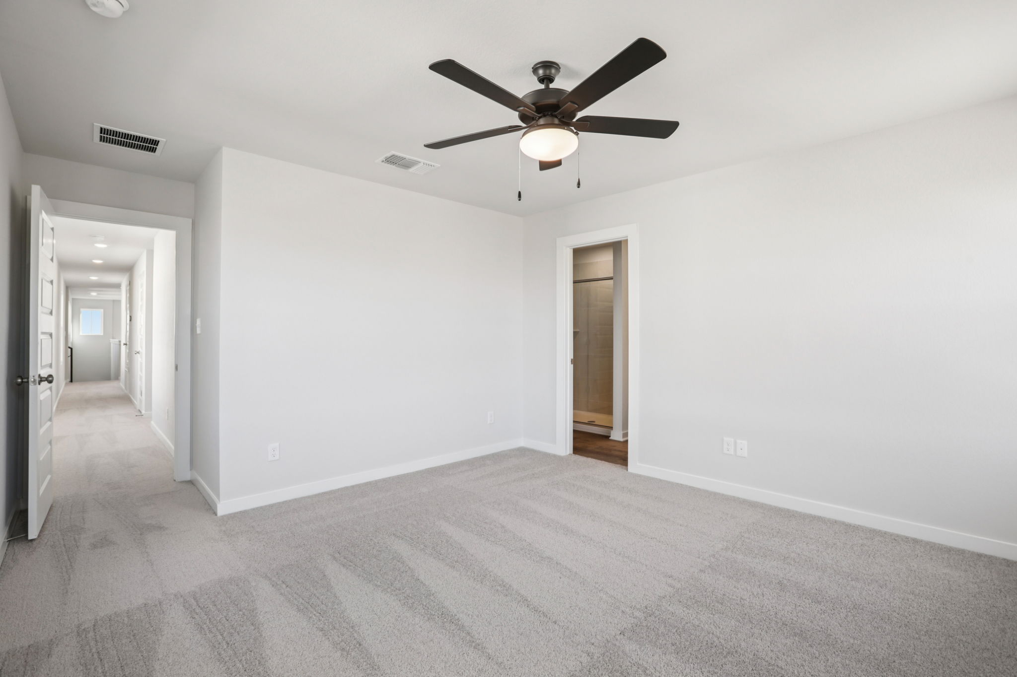 A room with a ceiling fan and a door.