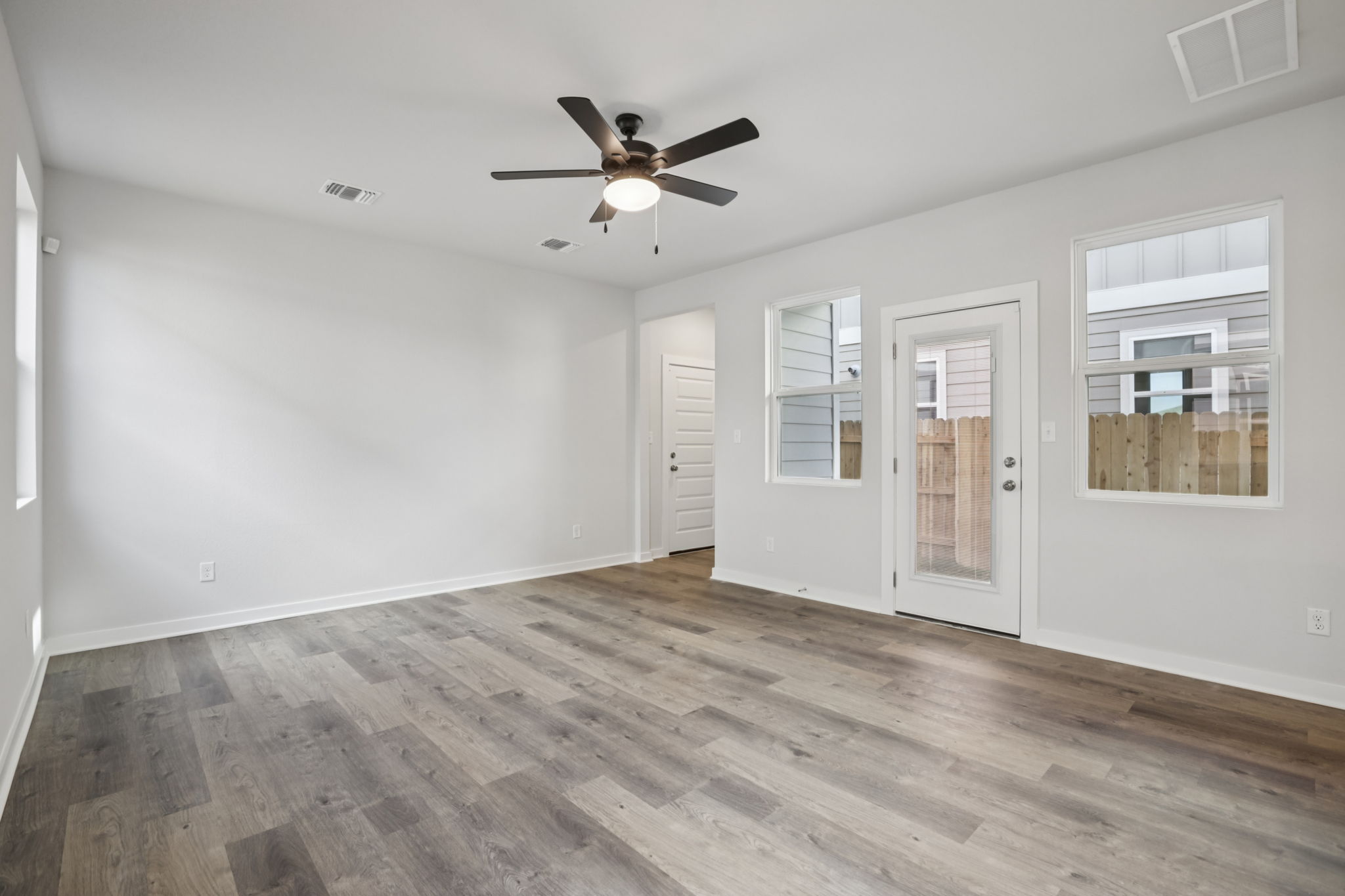 A room with a ceiling fan and a wood floor.