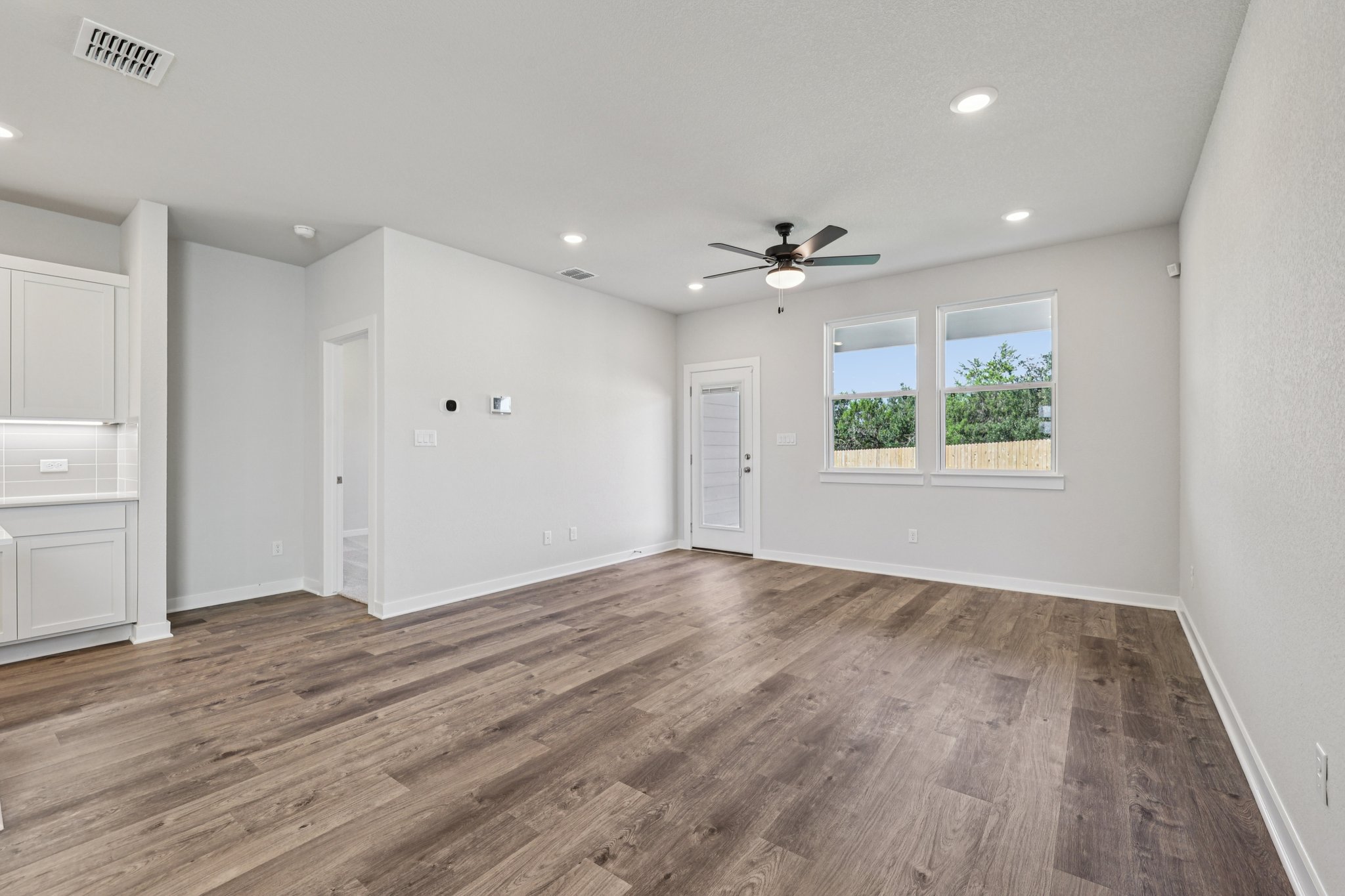 A large empty room with a wood floor and a ceiling fan.