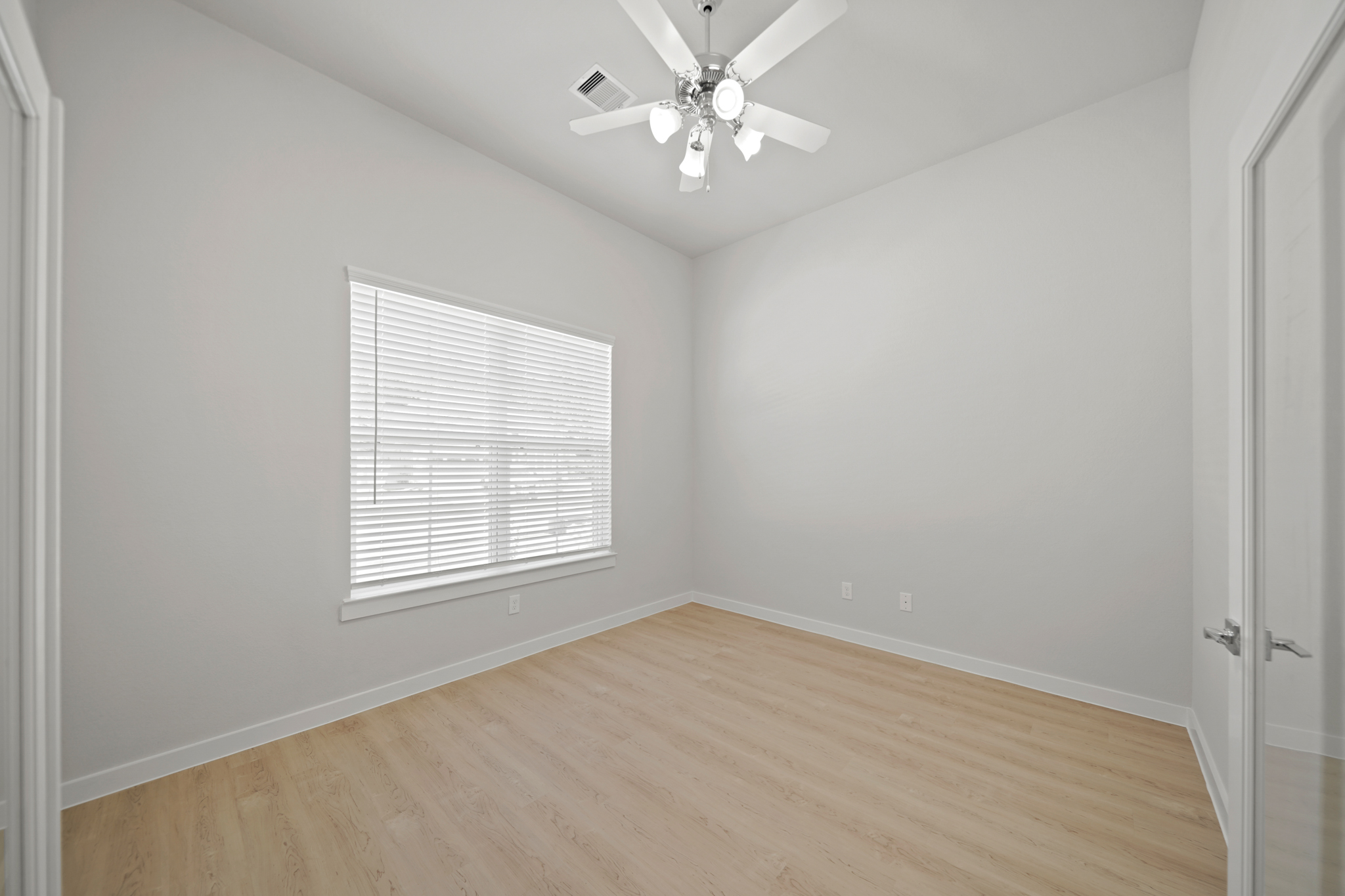 A room with a ceiling fan and a wood floor.