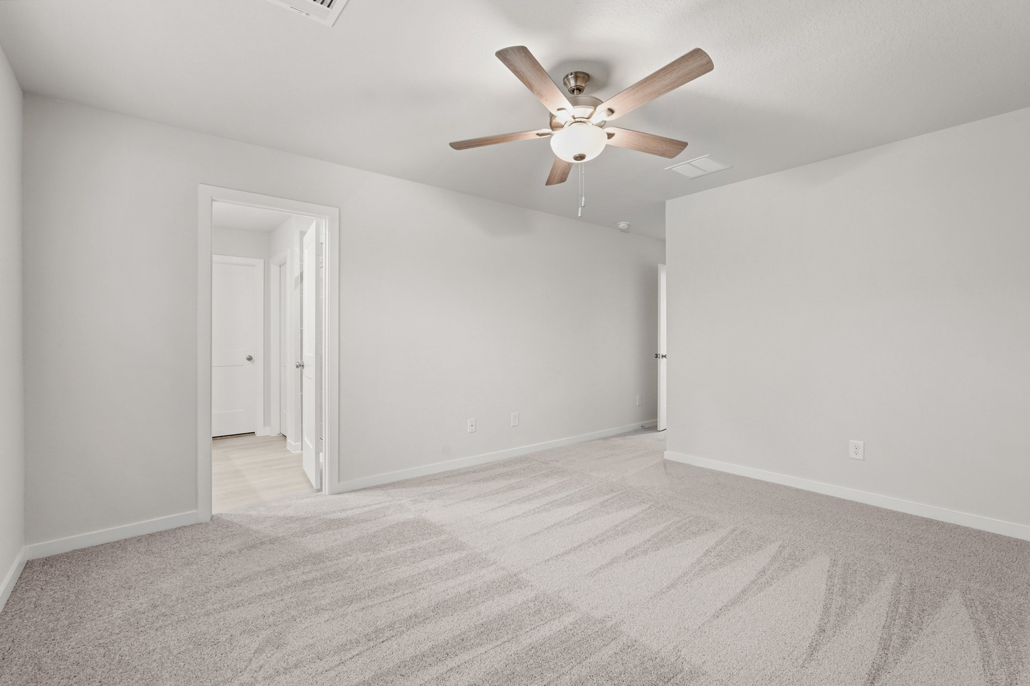 A room with a ceiling fan and white walls.