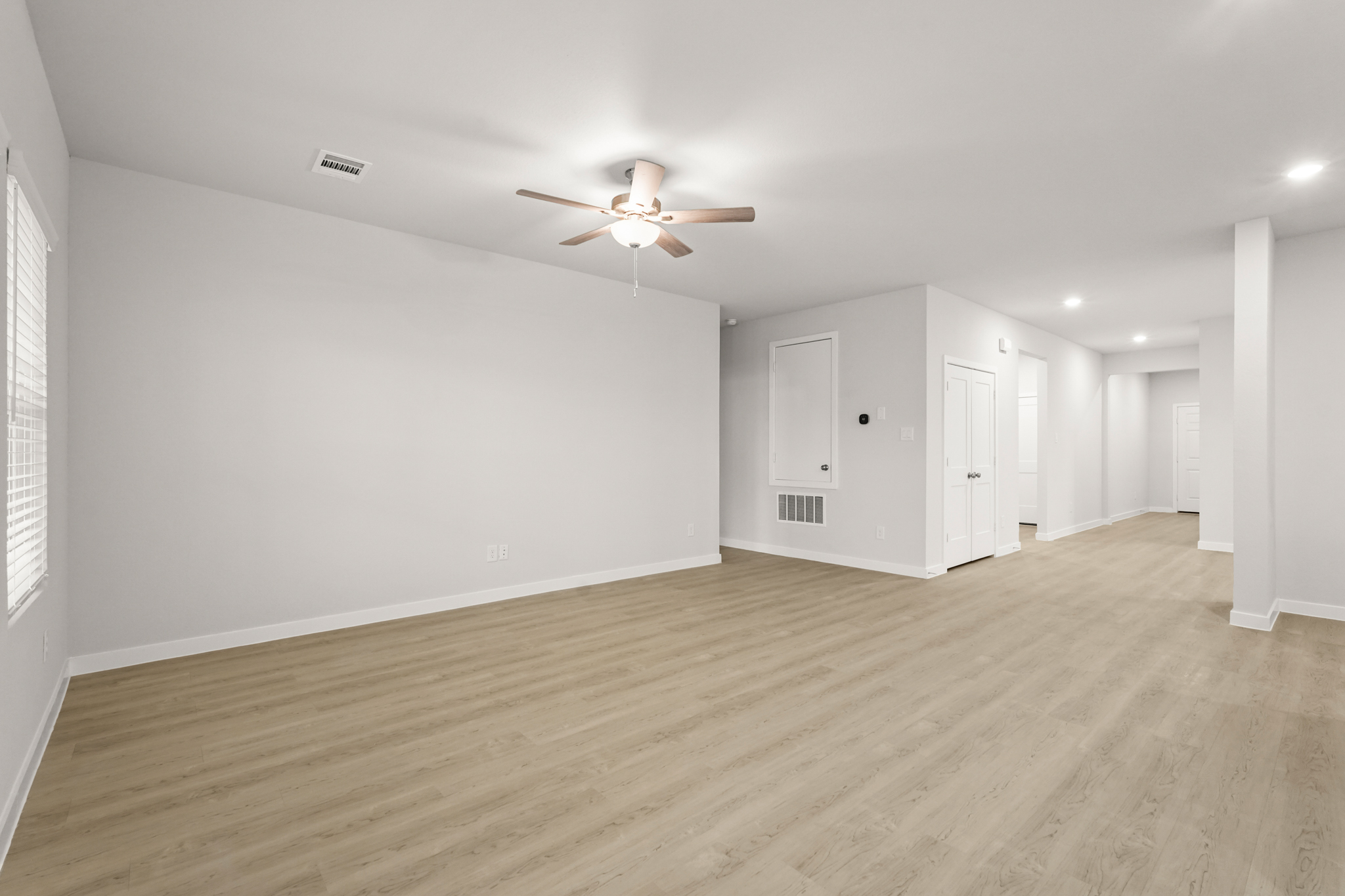 A room with a ceiling fan and white walls.