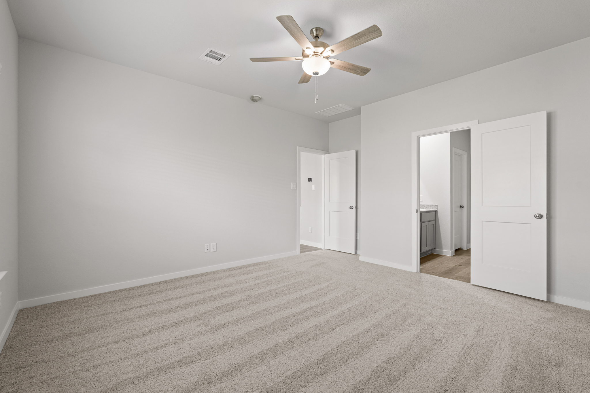 A room with a ceiling fan and white doors.