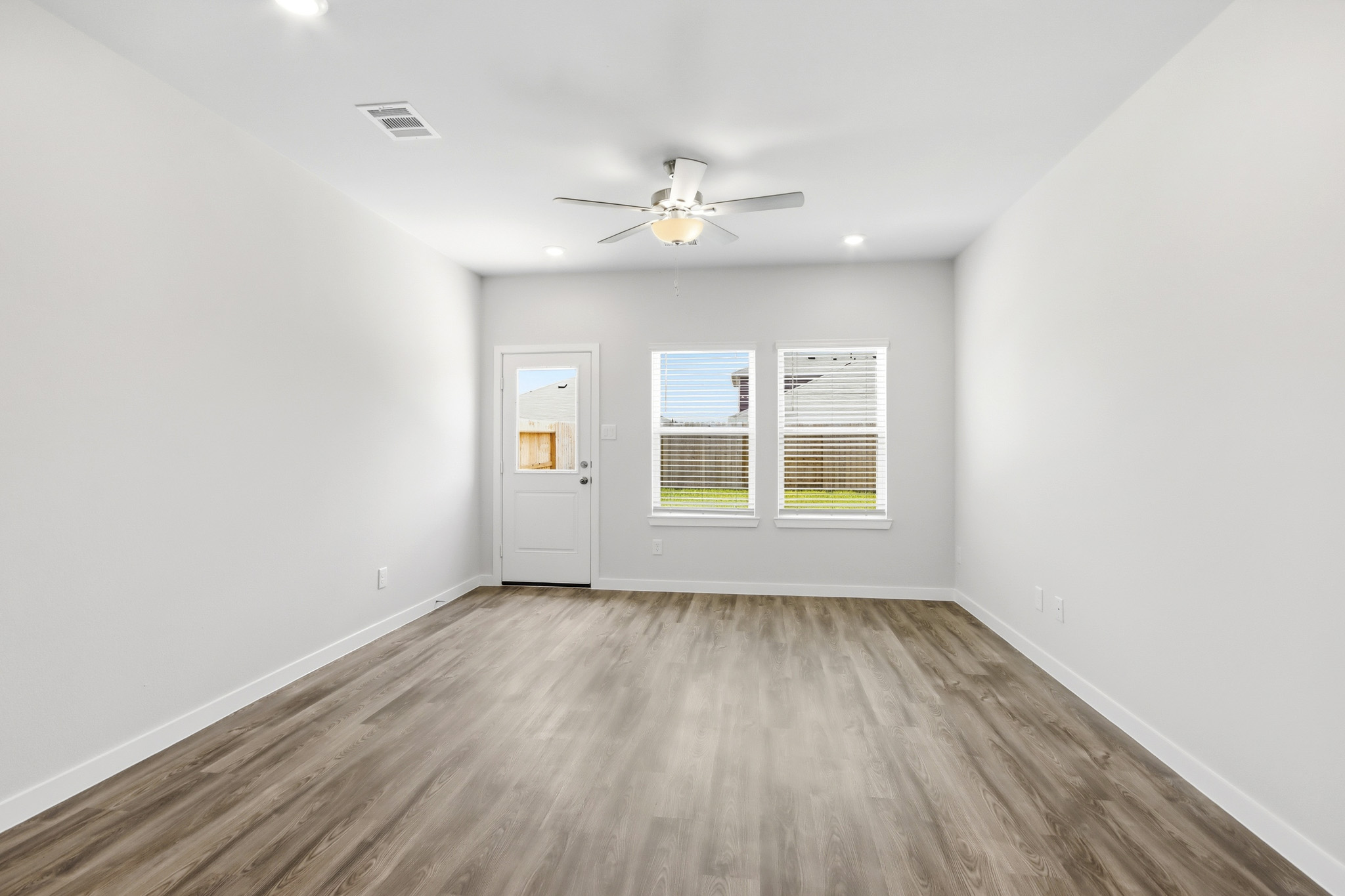 A room with a ceiling fan and a wood floor.