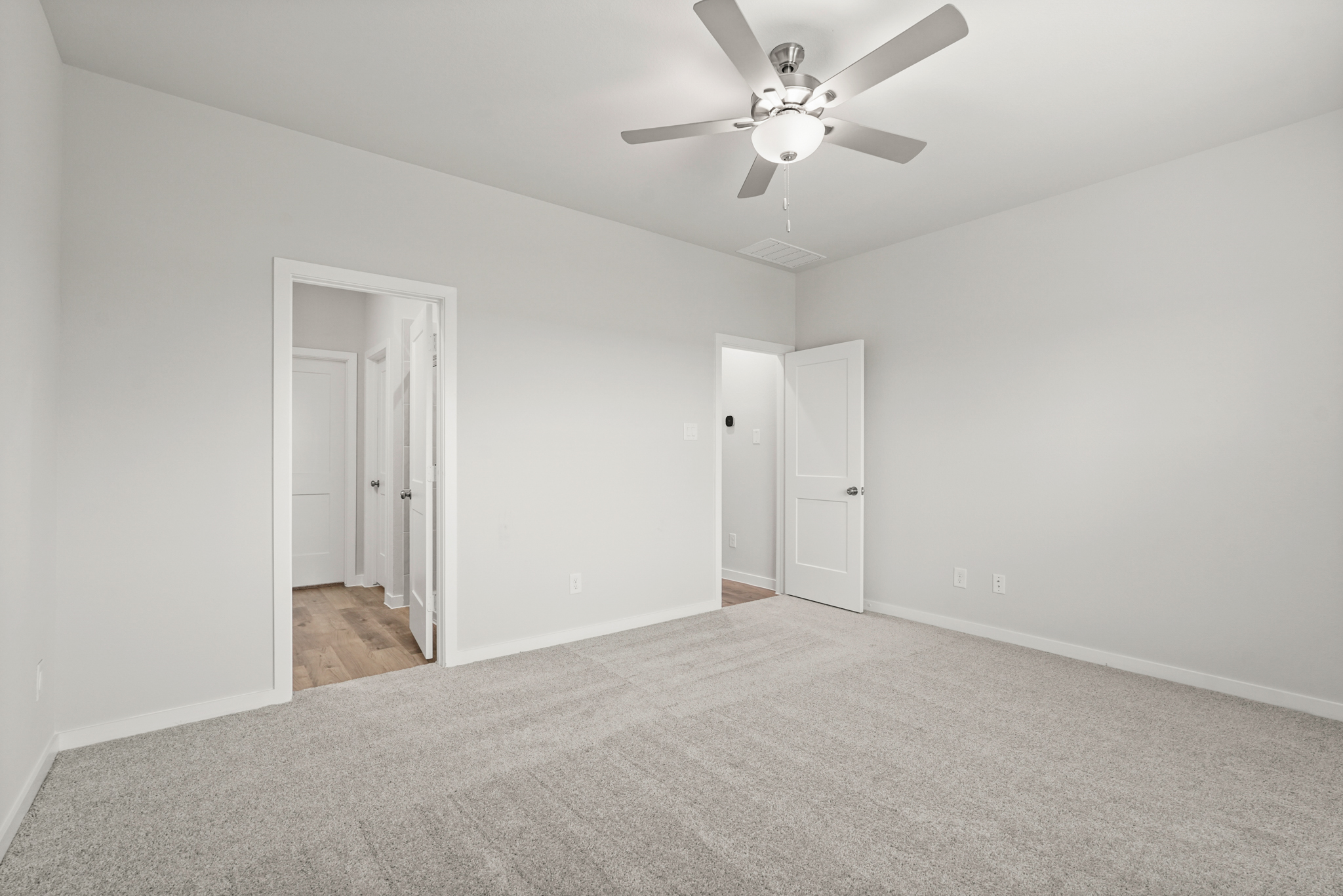 A room with a ceiling fan and white doors.