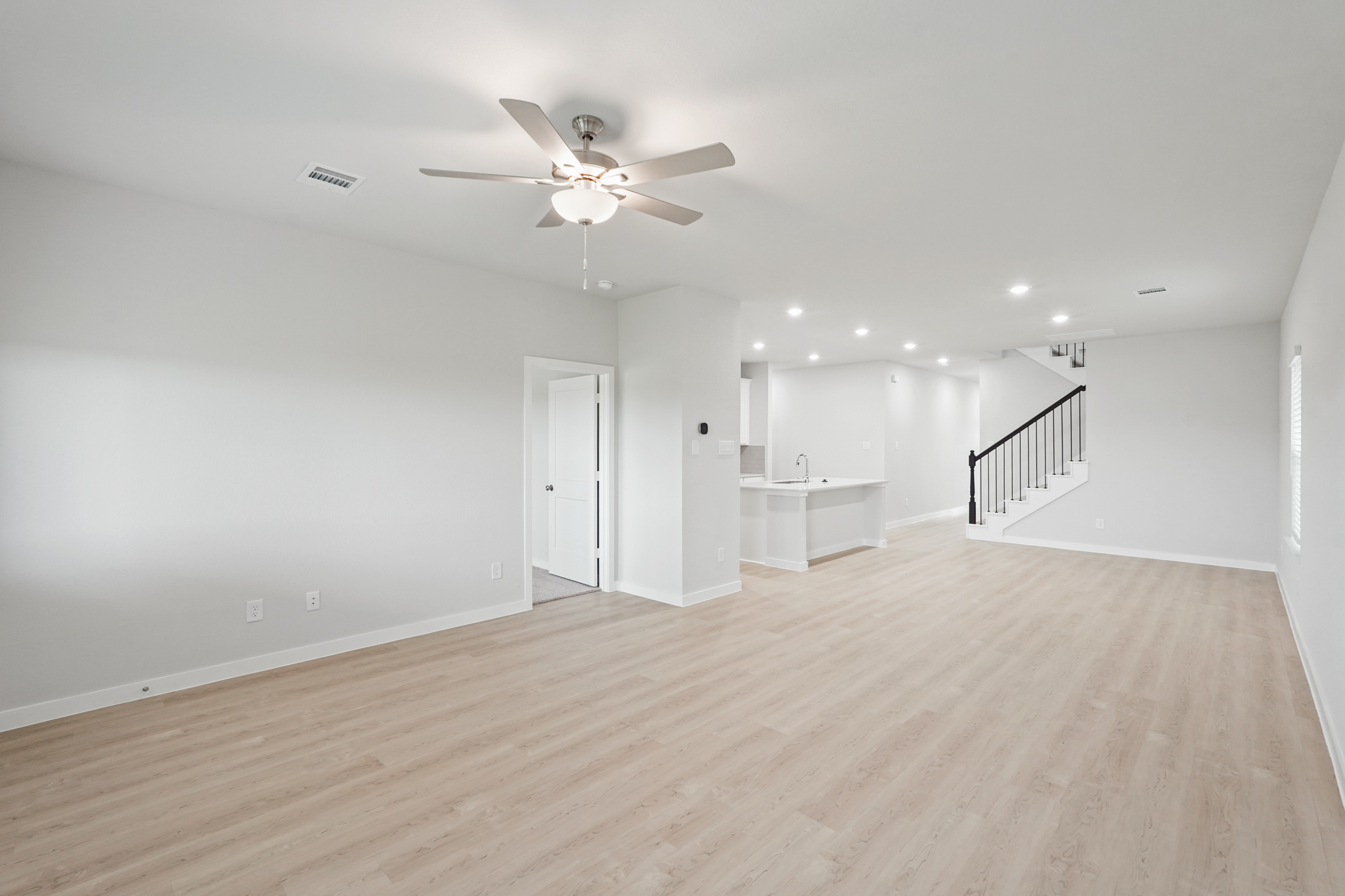 A large empty room with a ceiling fan and a wood floor.