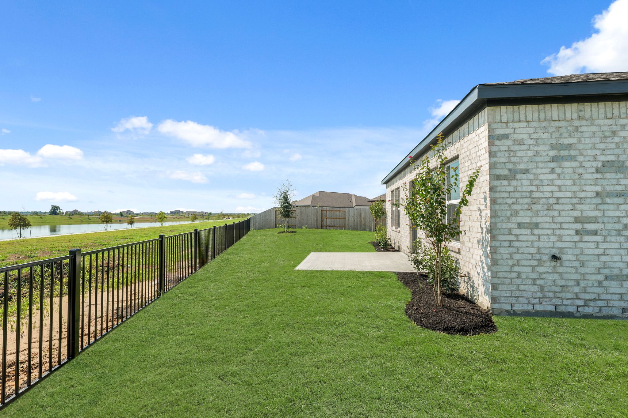 A fenced in yard with a brick building and a tree.