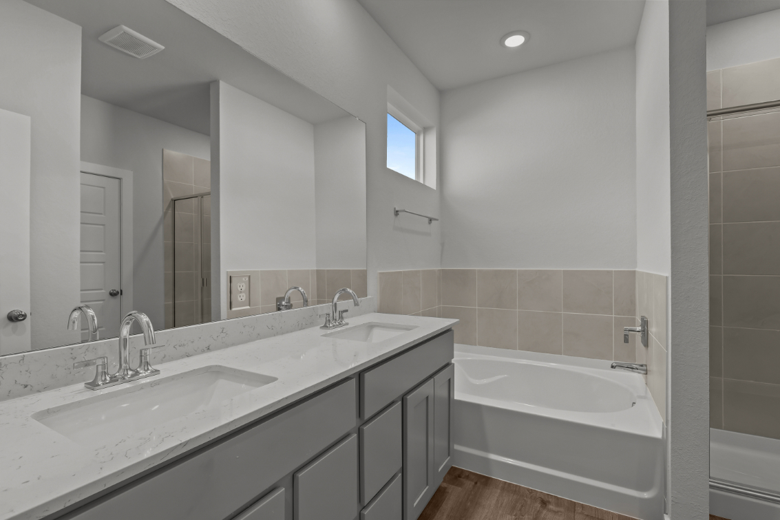 A bathroom with a tub sink and mirror.