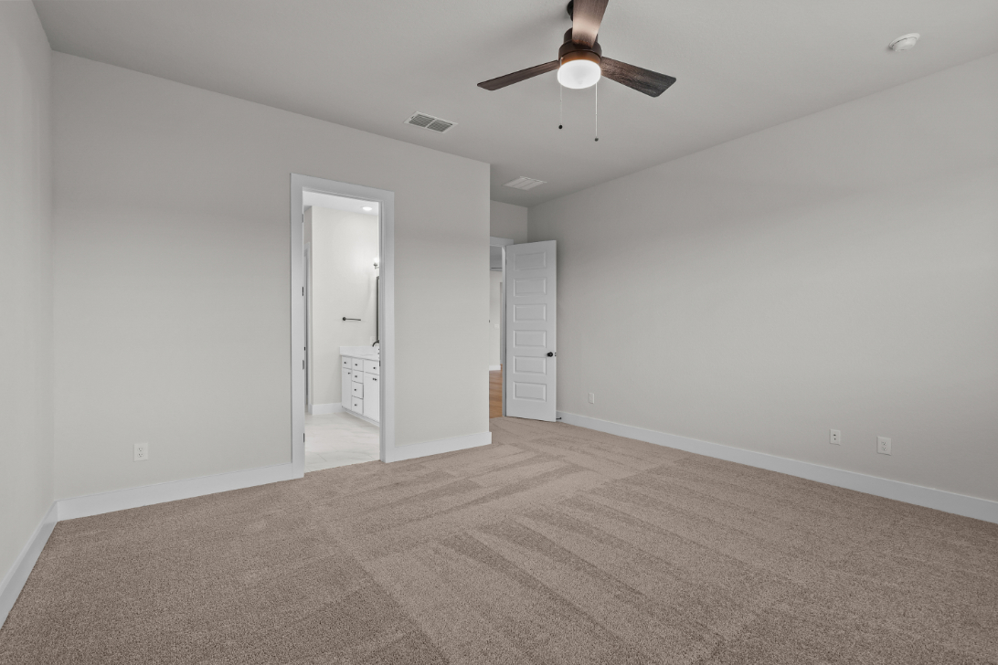 A room with a ceiling fan and a carpet.