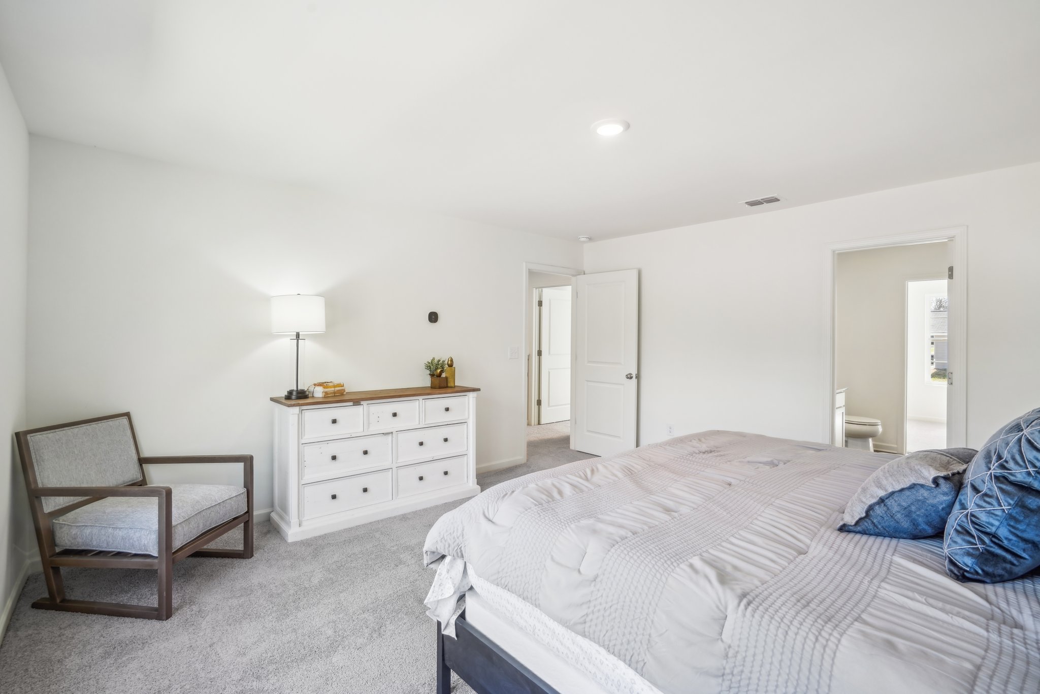 A bedroom with a bed and a chair.